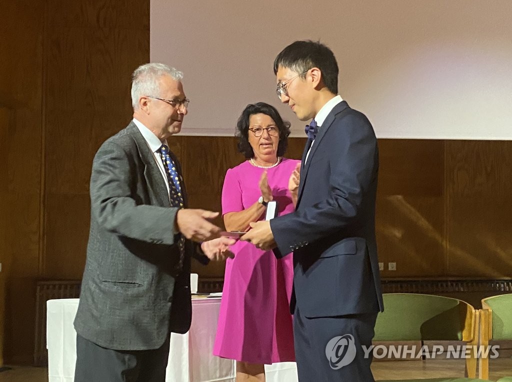June Huh (R), a Korean American mathematician and professor at Princeton University, receives the 2022 Fields Prize for Mathematics from International Mathematical Union President Carlos E. Kenig during the International Congress of Mathematicians 2022 in Helsinki, Finland, on July 5, 2022. (Yonhap)