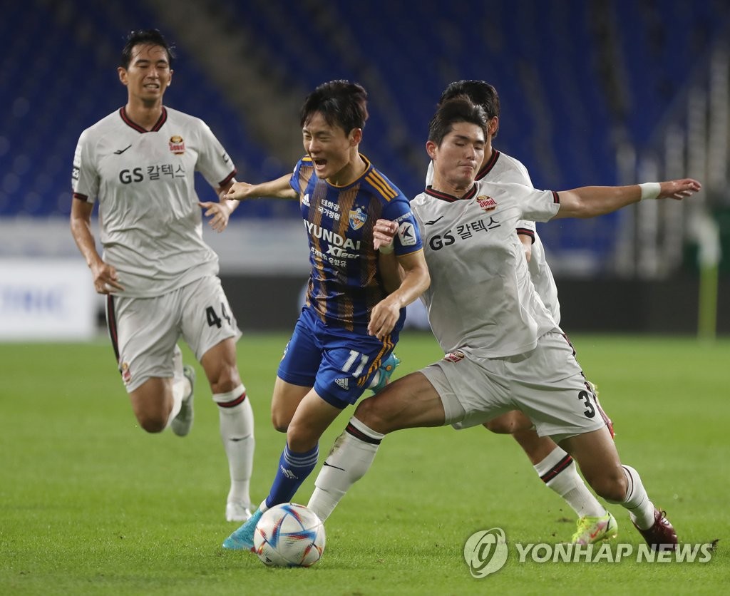 Um Won-sang of Ulsan Hyundai FC (C) and Lee Sang-min of FC Seoul battle for the ball during their clubs' K League 1 match at Munsu Football Stadium in Ulsan, 310 kilometers south of Seoul, on Aug. 2, 2022. (Yonhap)