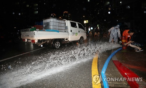 침수된 도로에서 물 빼내는 시민과 소방관