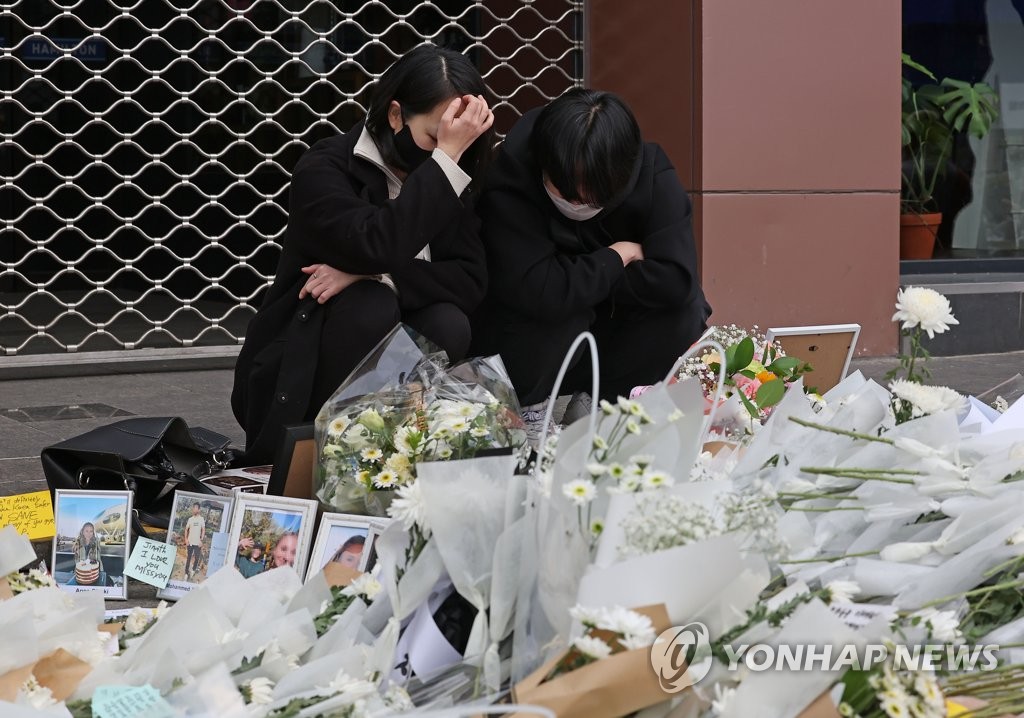 Unos dolientes lloran, el 3 de noviembre de 2022, en un altar conmemorativo provisional, frente a una estación del metro del barrio de Itaewon, en Seúl, que fue instalado en honor a las víctimas de la estampida del 29 de octubre.