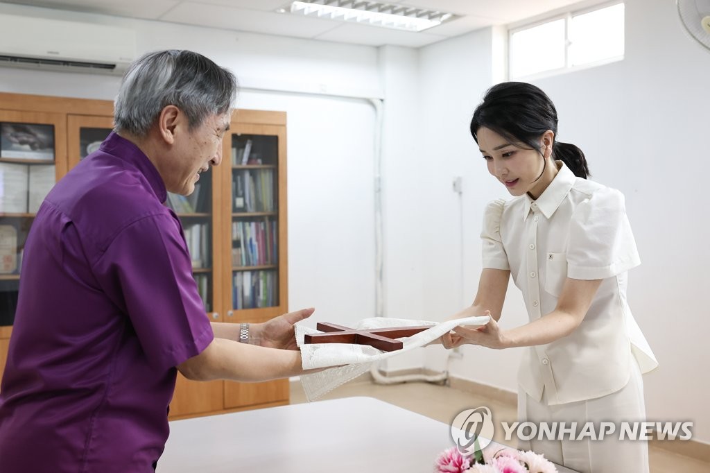 First lady Kim Keon-hee (R) receives a cross from Lee Young-don, chief of Hebron Medical Center, at the hospital in Phnom Penh on Nov. 13, 2022, in this photo provided by the presidential office. (PHOTO NOT FOR SALE) (Yonhap)
