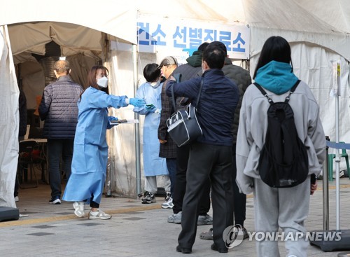 Des travailleurs médicaux aident les visiteurs à se faire tester contre le nouveau coronavirus (Covid-19) au centre médical public de Nowon à Séoul, le lundi 21 novembre 2022. 