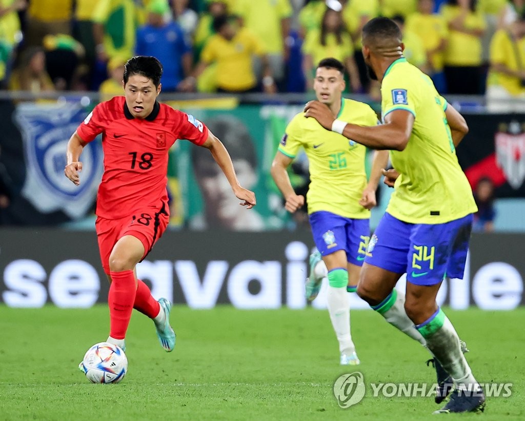 Lee Kang-in of South Korea (L) tries to dribble the ball past Bremer of Brazil during the countries' round of 16 match at the FIFA World Cup at Stadium 974 in Doha on Dec. 5, 2022. (Yonhap)
