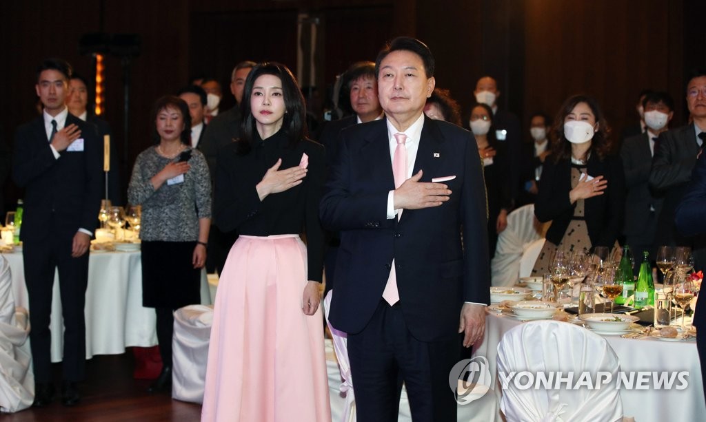 El presidente surcoreano, Yoon Suk Yeol (dcha., frente), y la primera dama, Kim Keon Hee (izda., frente), saludan a la bandera nacional, en una reunión con los residentes surcoreanos, celebrada, el 17 de enero de 2023 (hora local), en un hotel de Zúrich, Suiza. 