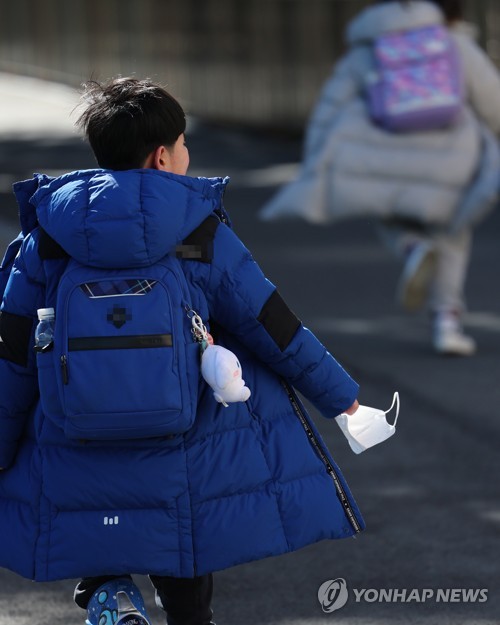 This photo taken Jan. 25, 2023, shows an elementary school student in the southeastern city of Busan coming home from school with a mask in his hand. The government plans to lift a mask mandate for most indoor public spaces, including schools, on Jan. 30. (Yonhap)
