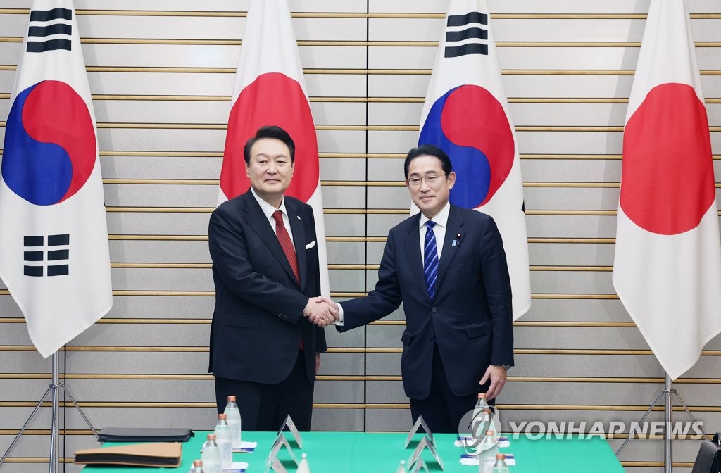 握手を交わす尹大統領（左）と岸田首相＝１６日、東京（聯合ニュース）