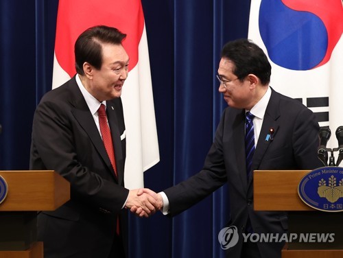 President Yoon Suk Yeol (L) shakes hands with Japanese Prime Minister Fumio Kishida at the end of their joint news conference after their summit in Tokyo on March 16, 2023. (Yonhap)