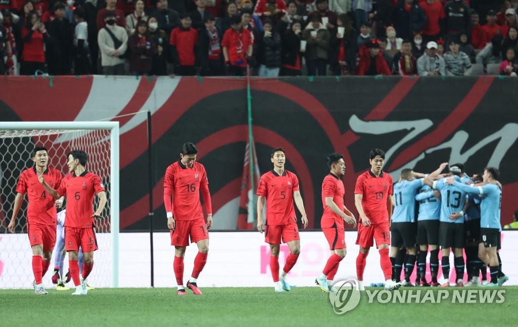 Los jugadores de la selección surcoreana (de rojo), reaccionan tras el gol del uruguayo Sebastián Coates, durante un partido amistoso contra Uruguay, organizado, el 28 de marzo de 2023, en el Estadio de la Copa Mundial de Seúl.