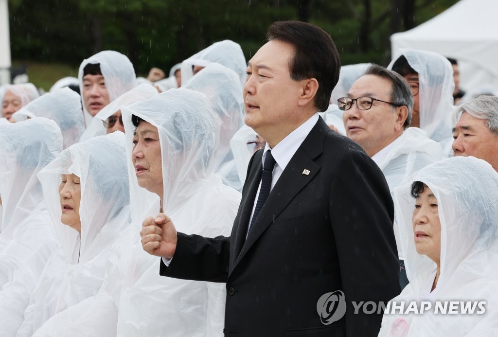 El presidente Yoon Suk Yeol (segundo desde la derecha), junto con un grupo de familias en duelo, canta la canción. "Marcha por el Amado" simbolizando un levantamiento a favor de la democracia de 1980, durante una ceremonia conmemorativa en un cementerio nacional en la ciudad de Gwangju, en el suroeste, el 18 de mayo de 2023, para conmemorar el 43.º aniversario del movimiento democrático que tuvo lugar en la ciudad.  (Yonhap)