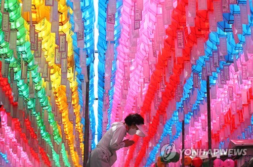A woman prays under colorful lanterns at a temple on Mount Palgong in North Gyeongsang Province on May 26, 2023, the eve of Buddha's Birthday. (Yonhap)