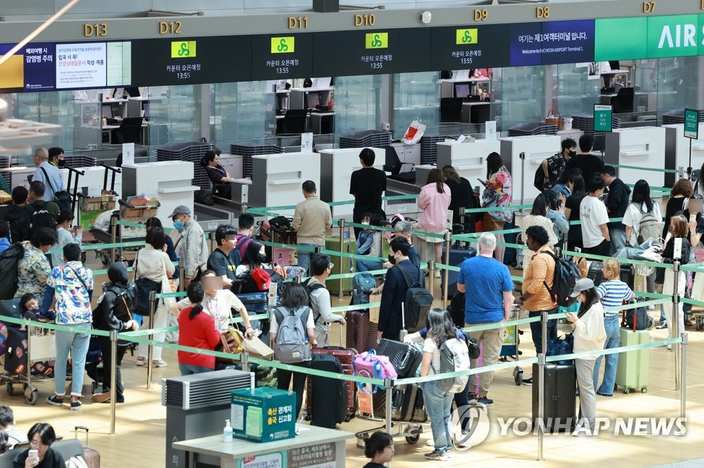 La foto de archivo, tomada el 2 de junio de 2023, muestra a viajeros esperando en fila, en un mostrador de facturación en el Aeropuerto Internacional de Incheon, al oeste de Seúl.