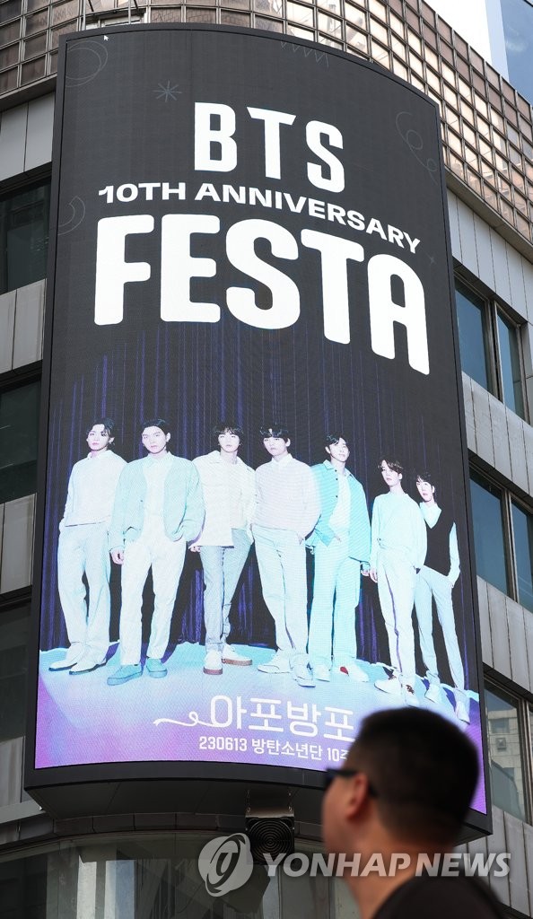 A tourist views an image of K-pop juggernaut BTS on a billboard in Seoul on June 12, 2023, as a two-week-long festival kicked off to celebrate its 10th debut anniversary. (Yonhap)