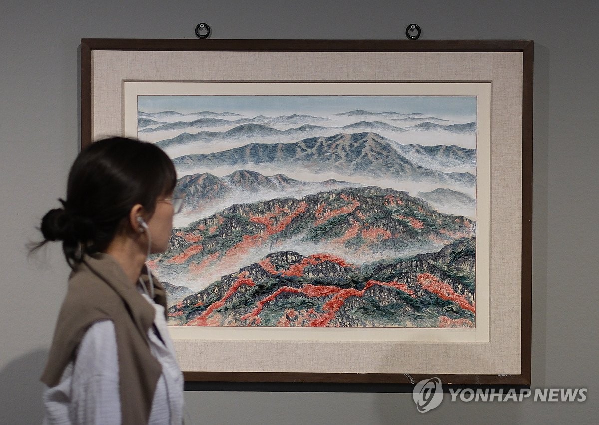 A visitor examines an embroidered piece featured in the exhibition, "Korean Embroidery in Modern Times: The Birds Trying to Catch the Sun," at the Deoksugung branch of the National Museum of Modern and Contemporary Art in Seoul on April 30, 2024. (Yonhap)